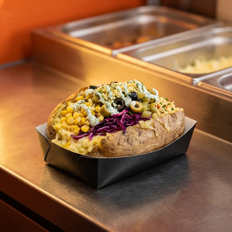 Kumpir mit Toppings auf der Edelstahltheke im Foodcontainer