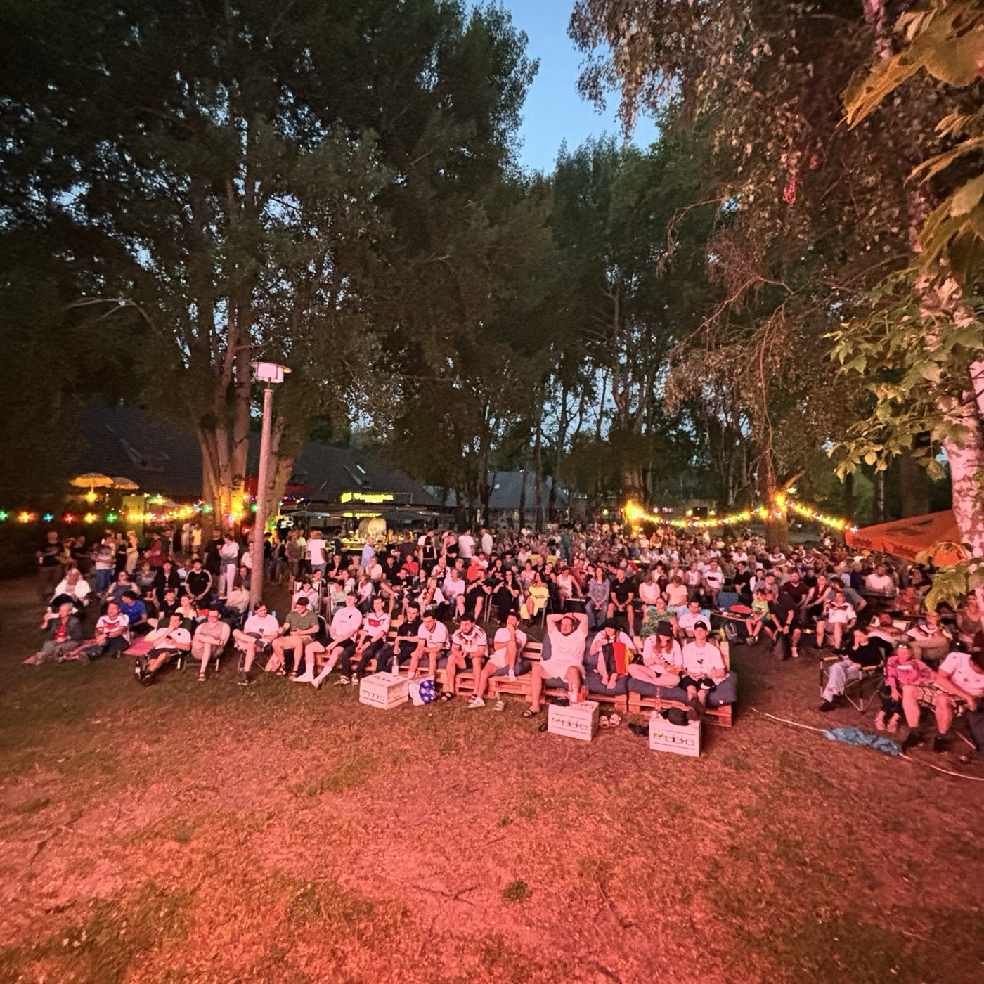 Publikum beim Public Viewing am Strandbad Rangsdorf unter Lichterketten